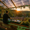 Professional DJ using energy-efficient DJ gear at a solar-powered outdoor festival.